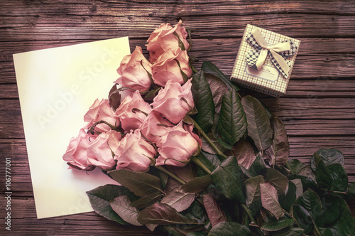 Pink roses over blank paper with gift box