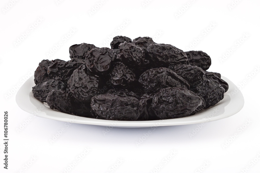 Raw organic prunes, dried plums, on the plate isolated on a white background Raw organic prunes, dried plums, on the plate isolated on a white background