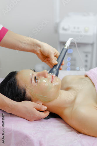 Young beautiful woman with dark hair gets procedure in the beauty salon photo