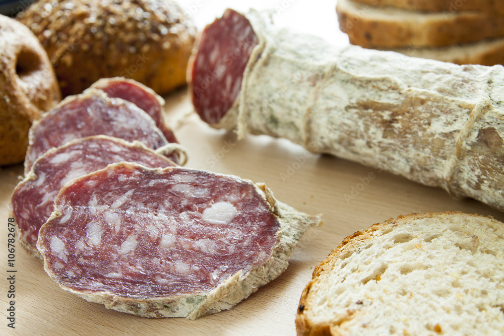 Salame casereccio a fette con pane integrale su tagliere di legno Salame casereccio a fette con pane integrale su tagliere di legno