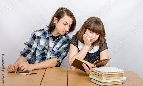 Подросток заглядывает в книгу, которую читает девочка