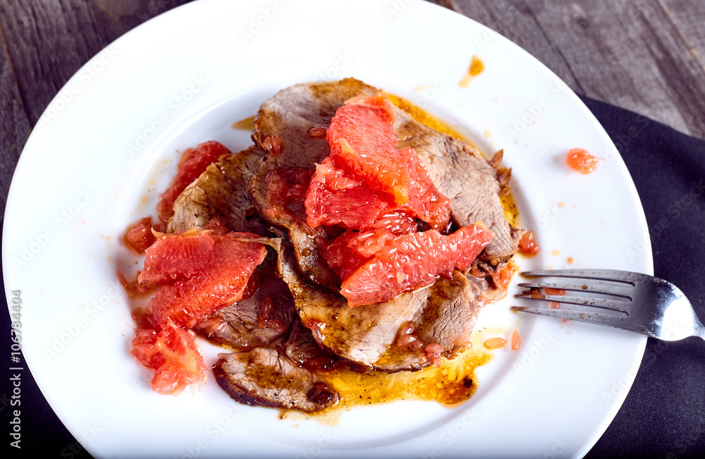 Beef with grapefruit sauce on wood background Beef with grapefruit sauce on wood background