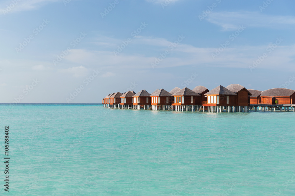 bungalow huts in sea water on exotic resort beach