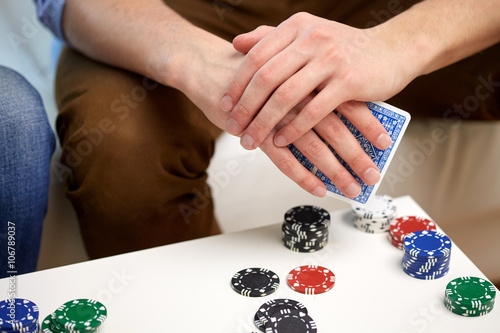close up of male hand with playing cards and chips