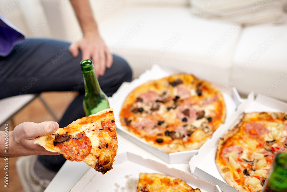 close up of man eating pizza with beer at home