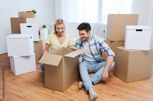 smiling couple with big boxes moving to new home