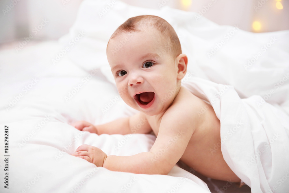 Naked adorable baby lying on soft bed, close up Naked adorable baby lying on soft bed, close up