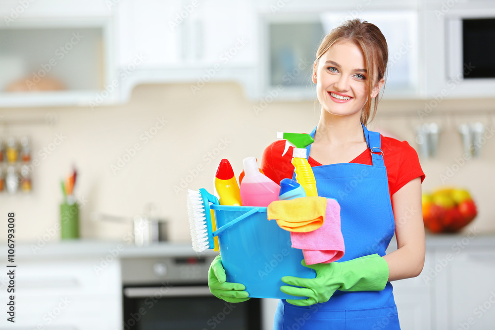 Cleaning concept. Young woman holds basin with washing fluids and rags in hands Cleaning concept. Young woman holds basin with washing fluids and rags in hands