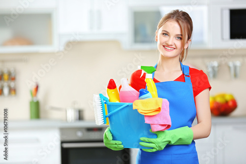 Cleaning concept. Young woman holds basin with washing fluids and rags in hands