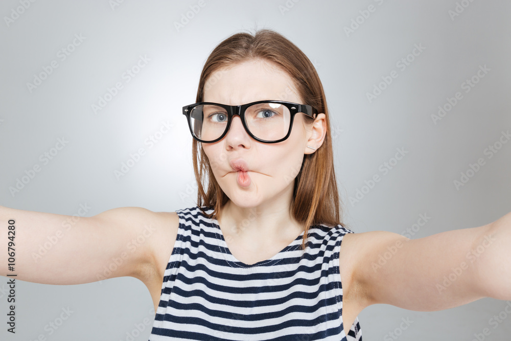 Funny girl in glasses making funny face and taking selfie Funny girl in glasses making funny face and taking selfie