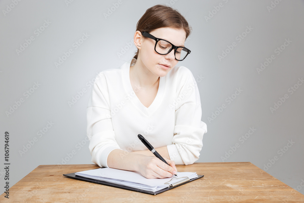 Teenage girl sitting and writing on clipboard Teenage girl sitting and writing on clipboard