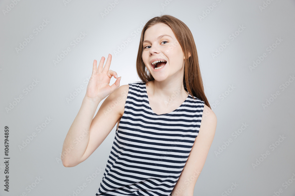 Happy attractive teenage girl in striped top showing ok sign Happy attractive teenage girl in striped top showing ok sign