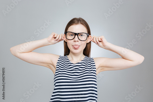 Teenage girl in glasses showing tongue and making funny face