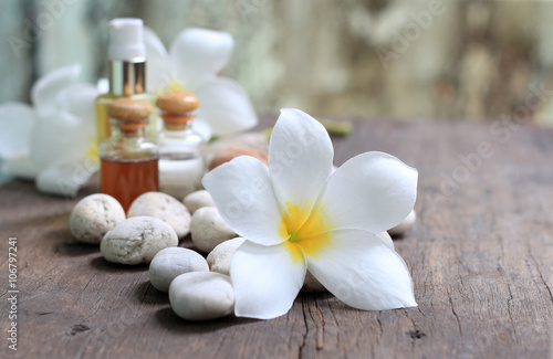 Plumeria flowers with aroma oils on wooden blur background