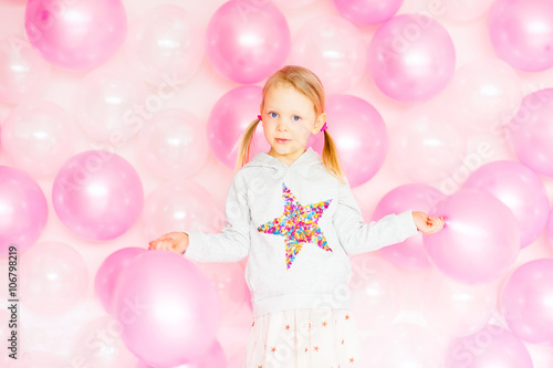 little girl playing with pink balloons
