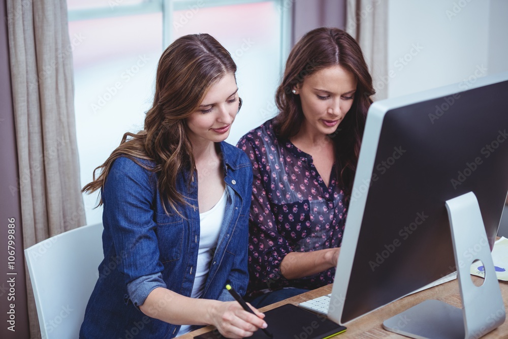 Two beautiful woman using computer and pen tablet Two beautiful woman using computer and pen tablet