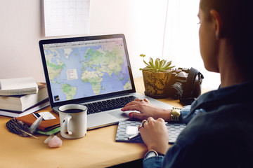 stylish young girl hipster looking at map on laptop, freelance a