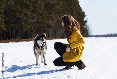 young girl playing with a dog in winter park. pets and the owner