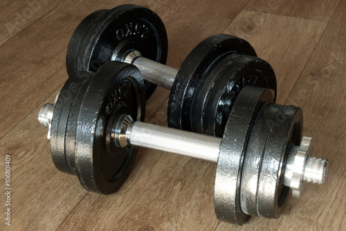 Iron dumbbells on hardwood floor. Weightlifting.