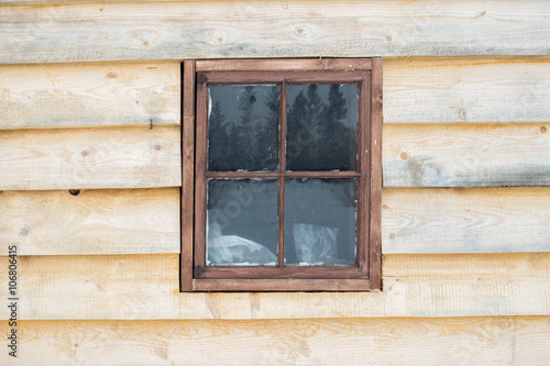 Old wood framed window in a exterior wall of a building with unfinished wood planks