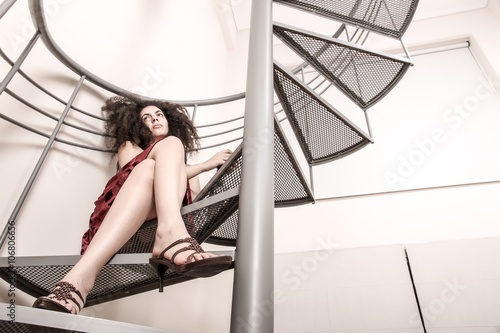 A young brazilian woman sitting on the stairs with a glass of red wine.