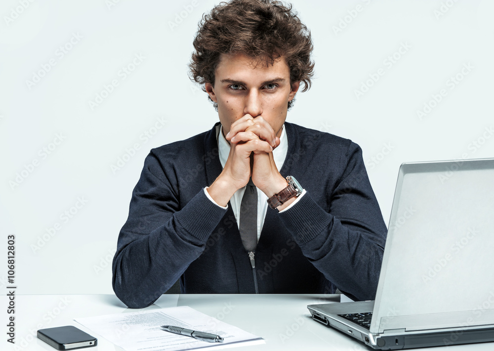 Deep in thought man. Businessman at the workplace working with computer on gray background.