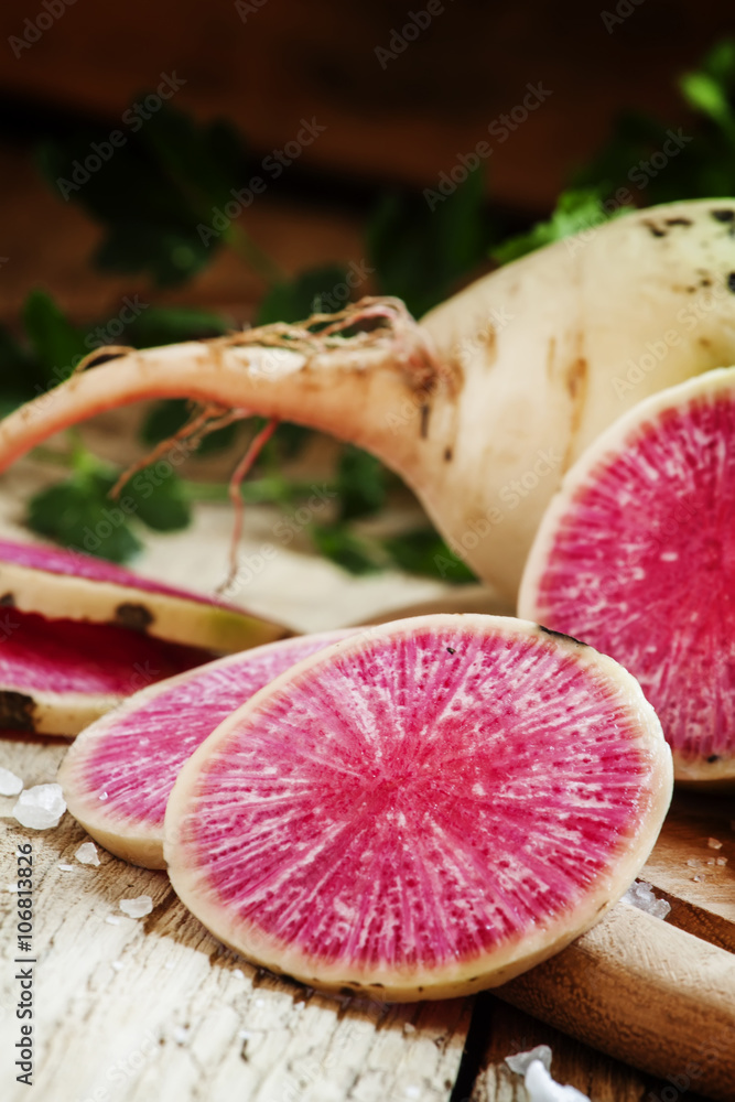 Slices of pink watermelon radish on a wooden table with parsley Slices of pink watermelon radish on a wooden table with parsley