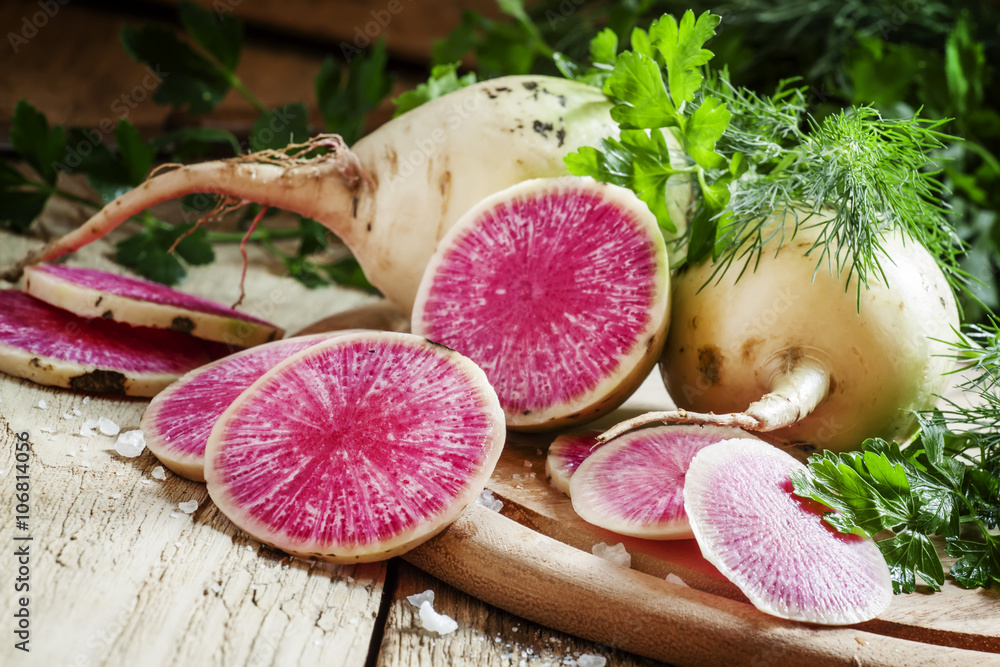 Slices of pink watermelon radish on a wooden table with parsley Slices of pink watermelon radish on a wooden table with parsley