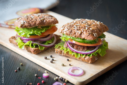 fresh home made burgers with grain bread on wooden background