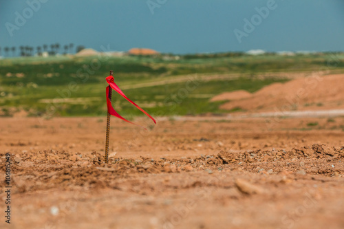 Metal survey peg with red flag on construction site