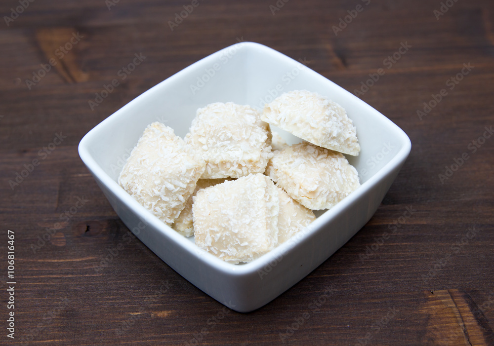 Cakes with coconut on a square bowl on wooden table