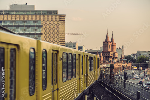 Yellow Subway train on trail to the historical bridge (Oberbaumbruecke) in Berlin, Germany, Europe, Vintage filtered style
