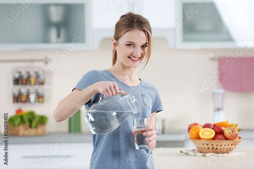 Young woman pouring water f...