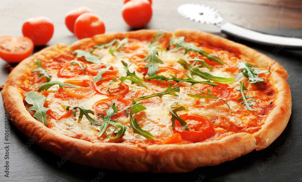 Margherita pizza with knife and tomatoes on slate plate