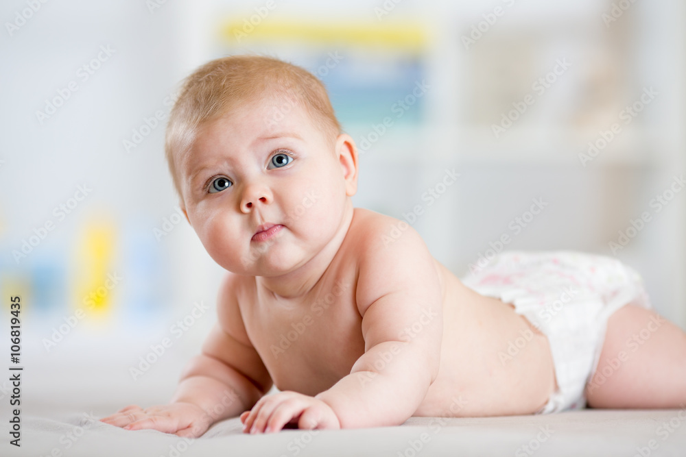 Infant child baby girl in diaper lying on bed in room Infant child baby girl in diaper lying on bed in room