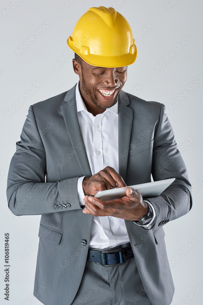 Black engineer professional looking at his tablet device smiling Black engineer professional looking at his tablet device smiling