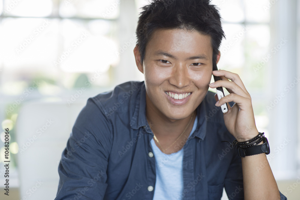 Korean man talking on cell phone indoors Korean man talking on cell phone indoors