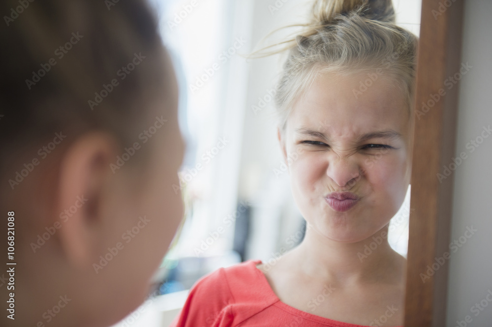 Caucasian girl scrunching up her face in mirror Caucasian girl scrunching up her face in mirror