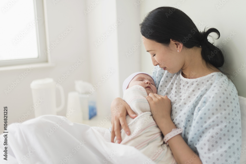 Asian mother holding newborn baby in hospital bed Asian mother holding newborn baby in hospital bed