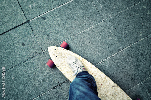 Point of view of a person leg on longboard on the city street. Personal perspective used. Blue color tone used.