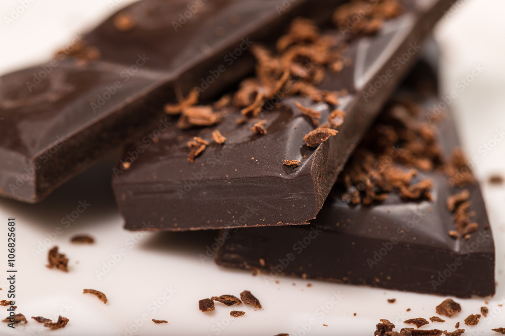 Pieces from a chocolate bar and chocolate crumbs on a white back Pieces from a chocolate bar and chocolate crumbs on a white back