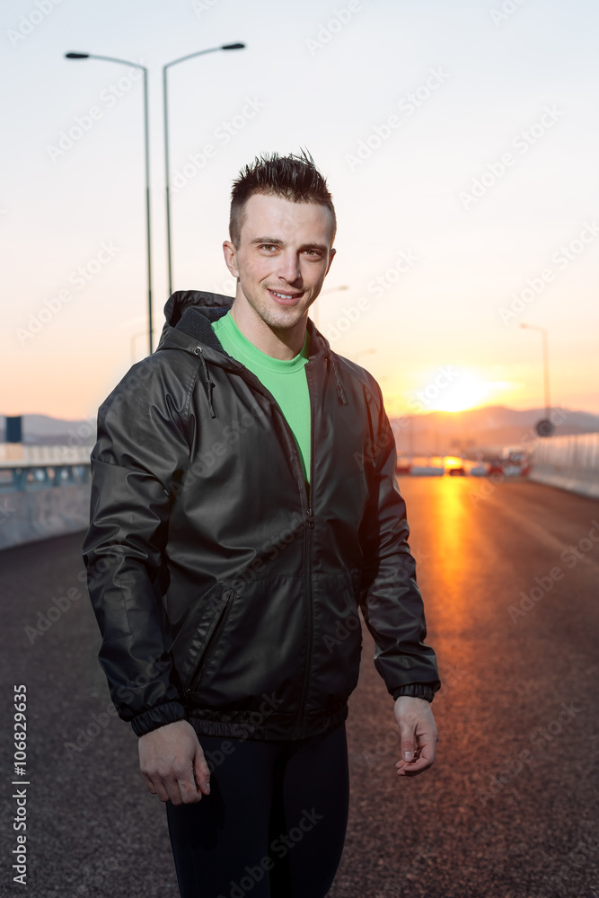 athletic man relaxing after hard work out, highway sunset