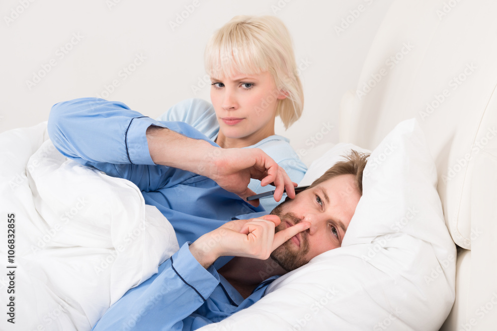 Obraz premium Woman Looking At Man Talking On Mobile Phone