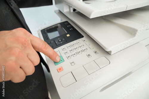 Close-up Of Businessman Pressing Printer's Button In Office