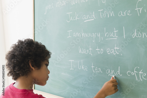 Mixed race boy writing on chalkboard in grammar lesson photo