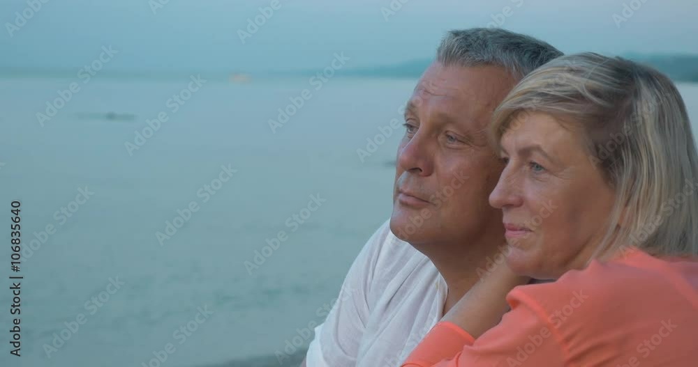 Woman embracing a man and they both staring at sea with distracted look. Time to dream and enjoy mature love Woman embracing a man and they both staring at sea with distracted look. Time to dream and enjoy mature love