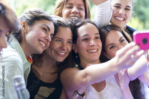 Hispanic women taking selfie at family reunion photo