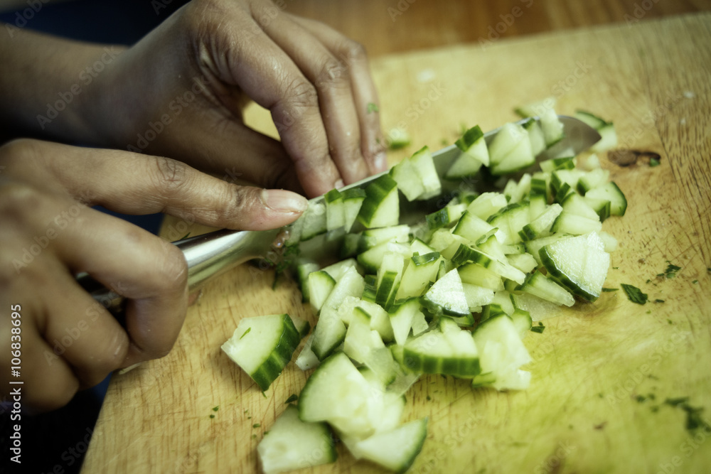 Close up of mixed race woman chopping cucumber in kitchen Close up of mixed race woman chopping cucumber in kitchen