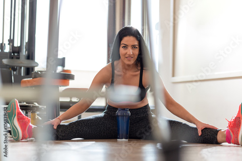 Young Woman Doing Stretching Exercises On The Floor At The Gym