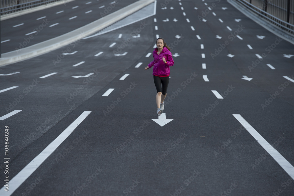 Women are running in the middle of the wide road wearing a sportswear